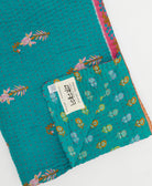 kantha quilt throw with a tag featuring the hand-stitched signature of the maker