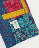 kantha quilt throw with a tag featuring the hand-stitched signature of the maker