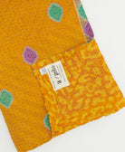 kantha quilt throw with a tag featuring the hand-stitched signature of the maker