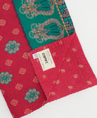 kantha quilt throw with a tag featuring the hand-stitched signature of the maker