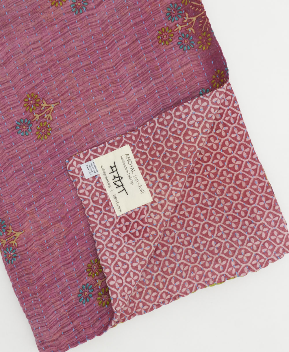 kantha quilt throw with a tag featuring the hand-stitched signature of the maker
