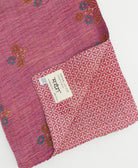 kantha quilt throw with a tag featuring the hand-stitched signature of the maker
