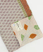 kantha quilt throw with a tag featuring the hand-stitched signature of the maker