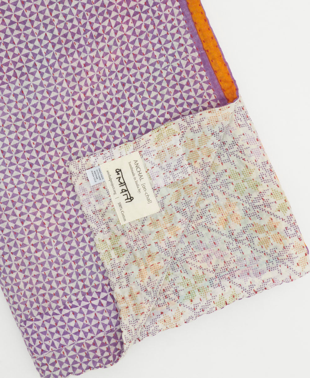 kantha quilt throw with a tag featuring the hand-stitched signature of the maker