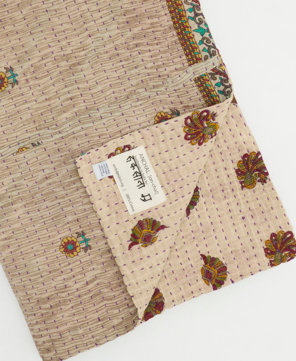 kantha quilt throw with a tag featuring the hand-stitched signature of the maker