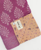 kantha quilt throw with a tag featuring the hand-stitched signature of the maker