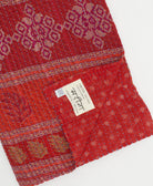 kantha quilt throw with a tag featuring the hand-stitched signature of the maker