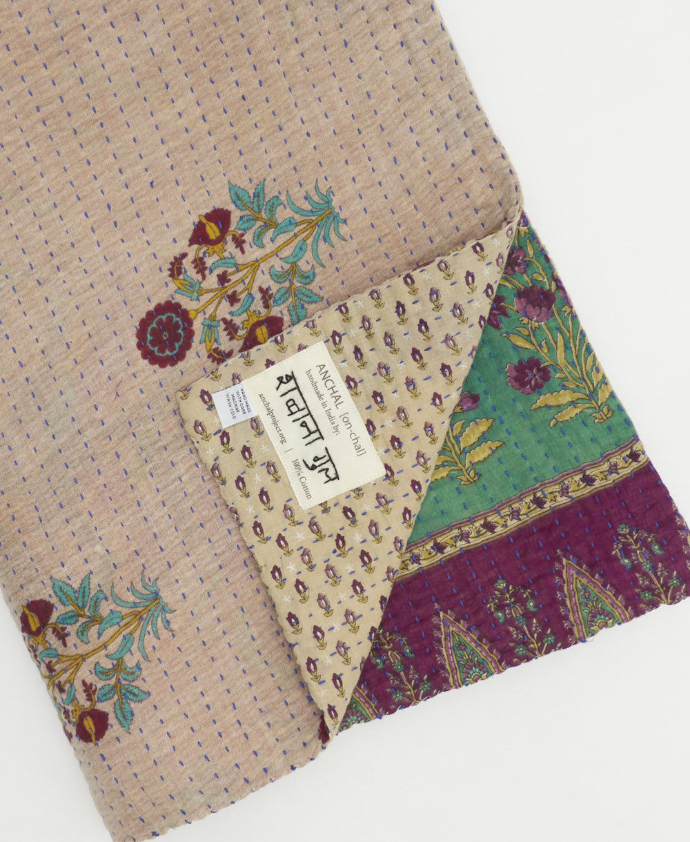 kantha quilt throw with a tag featuring the hand-stitched signature of the maker