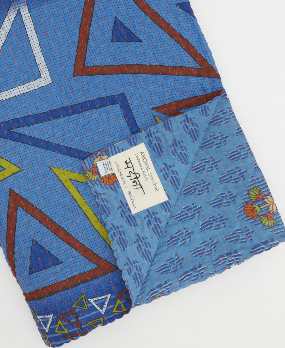 kantha quilt throw with a tag featuring the hand-stitched signature of the maker