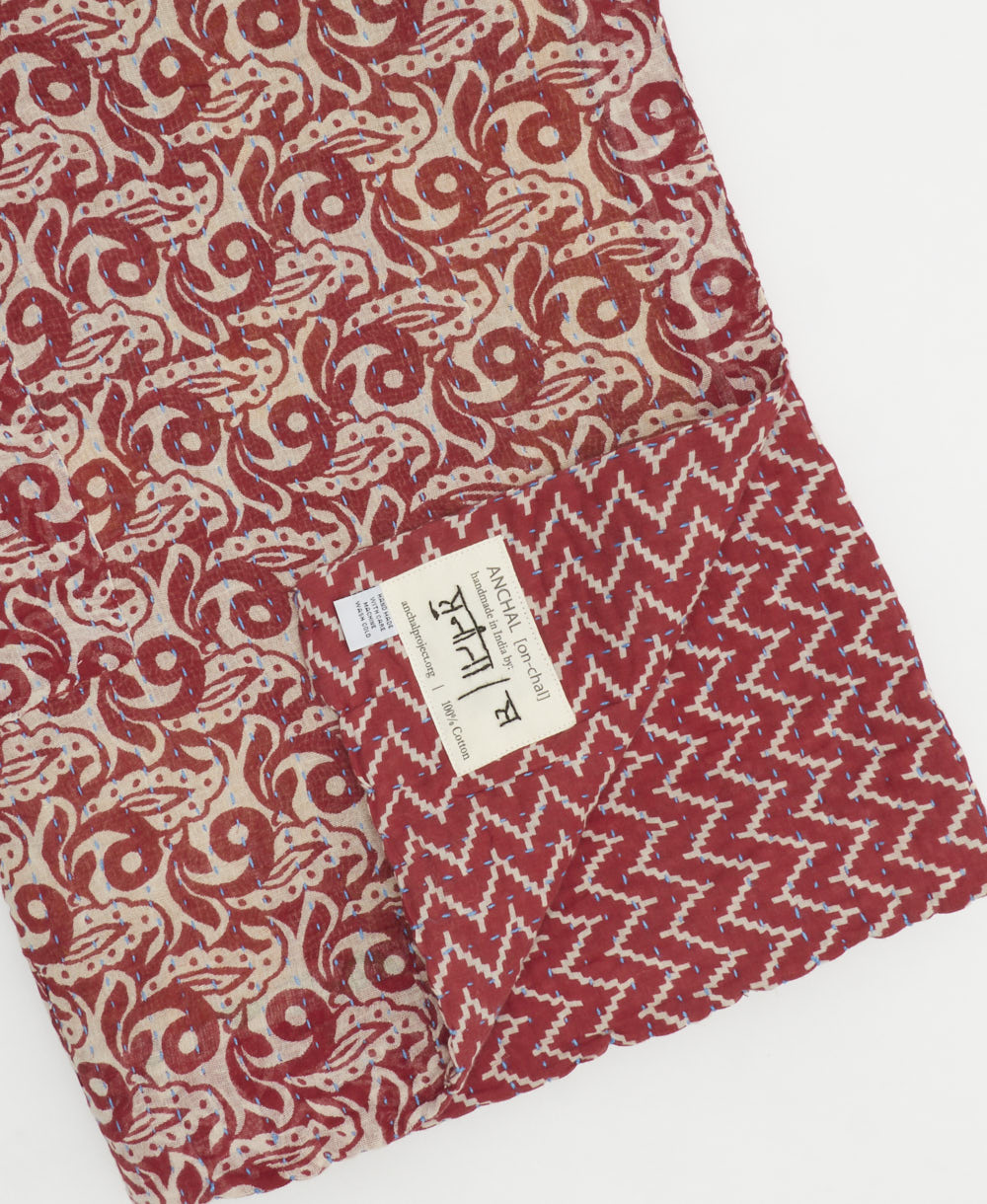 kantha quilt throw with a tag featuring the hand-stitched signature of the maker