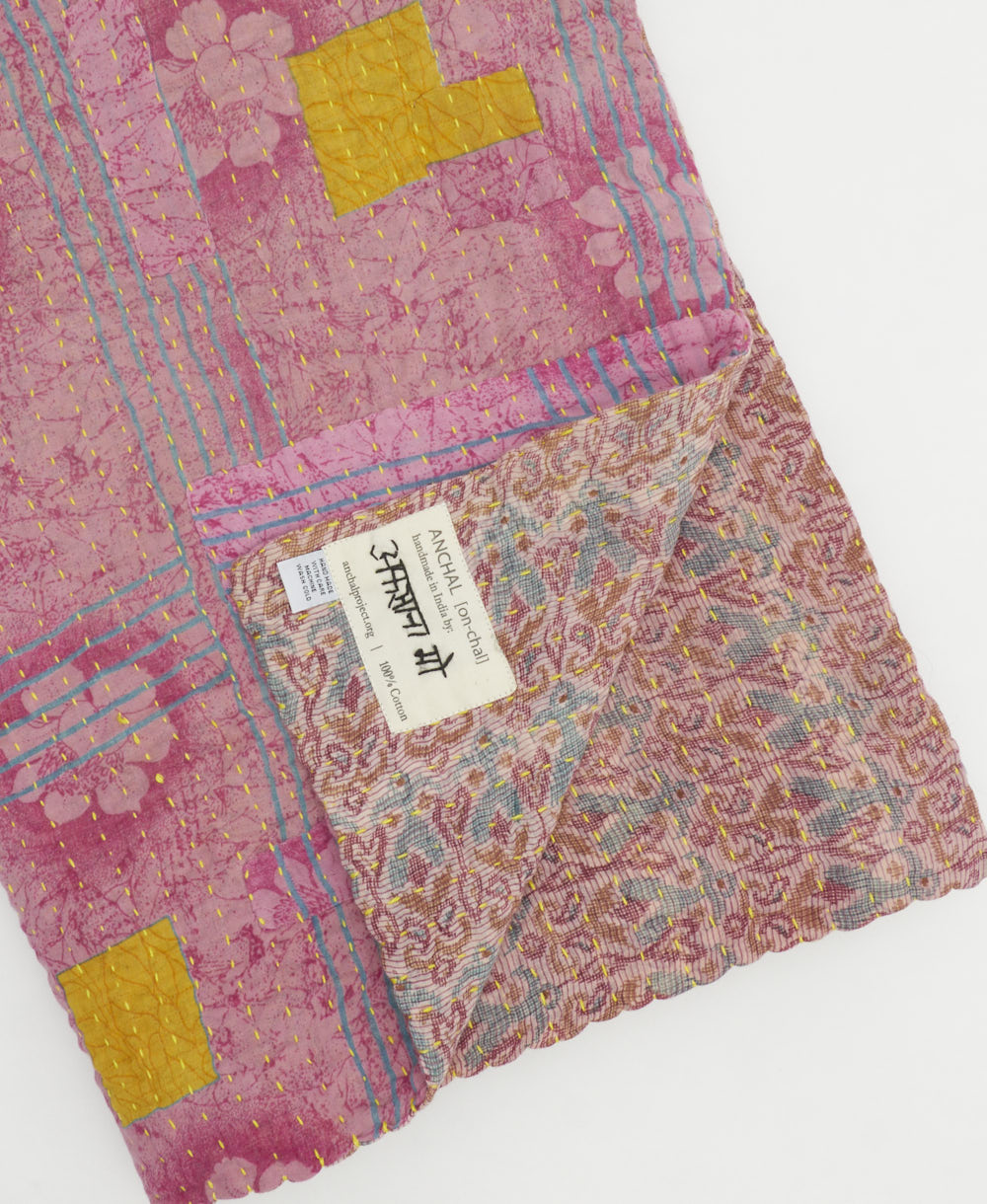 kantha quilt throw with a tag featuring the hand-stitched signature of the maker