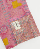 kantha quilt throw with a tag featuring the hand-stitched signature of the maker