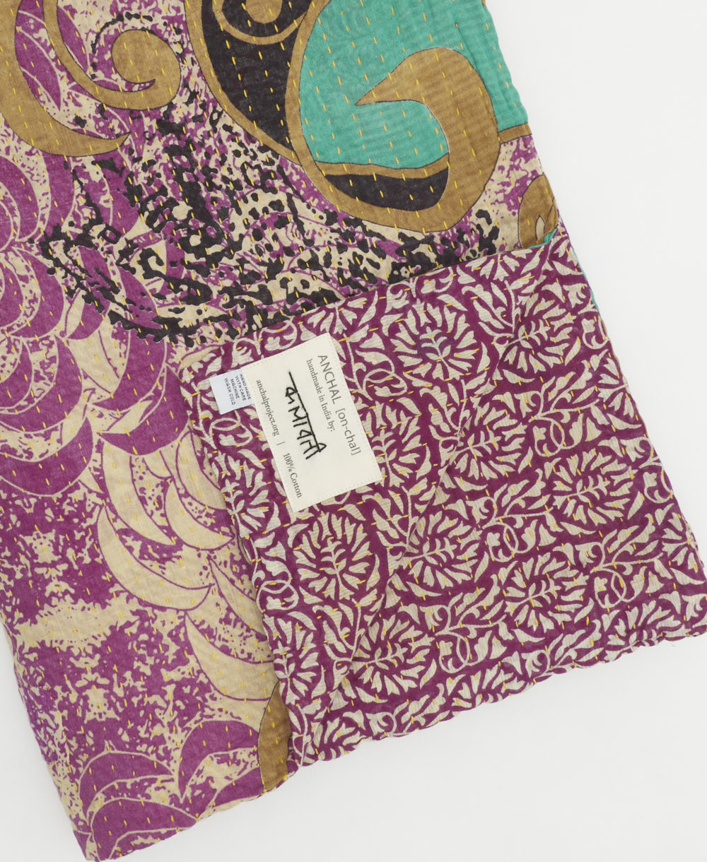 kantha quilt throw with a tag featuring the hand-stitched signature of the maker