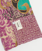 kantha quilt throw with a tag featuring the hand-stitched signature of the maker