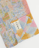 kantha quilt throw with a tag featuring the hand-stitched signature of the maker