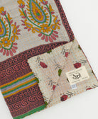 kantha quilt throw with a tag featuring the hand-stitched signature of the maker