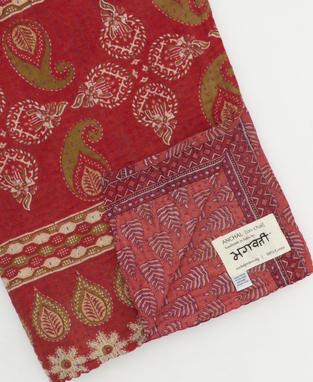 kantha quilt throw with a tag featuring the hand-stitched signature of the maker