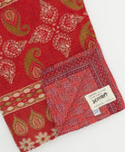 kantha quilt throw with a tag featuring the hand-stitched signature of the maker