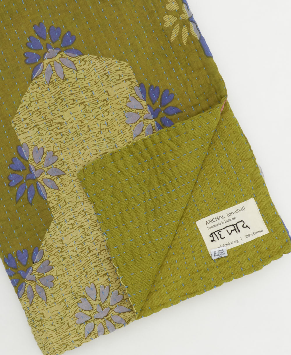 kantha quilt throw with a tag featuring the hand-stitched signature of the maker