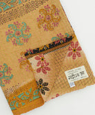 kantha quilt throw with a tag featuring the hand-stitched signature of the maker