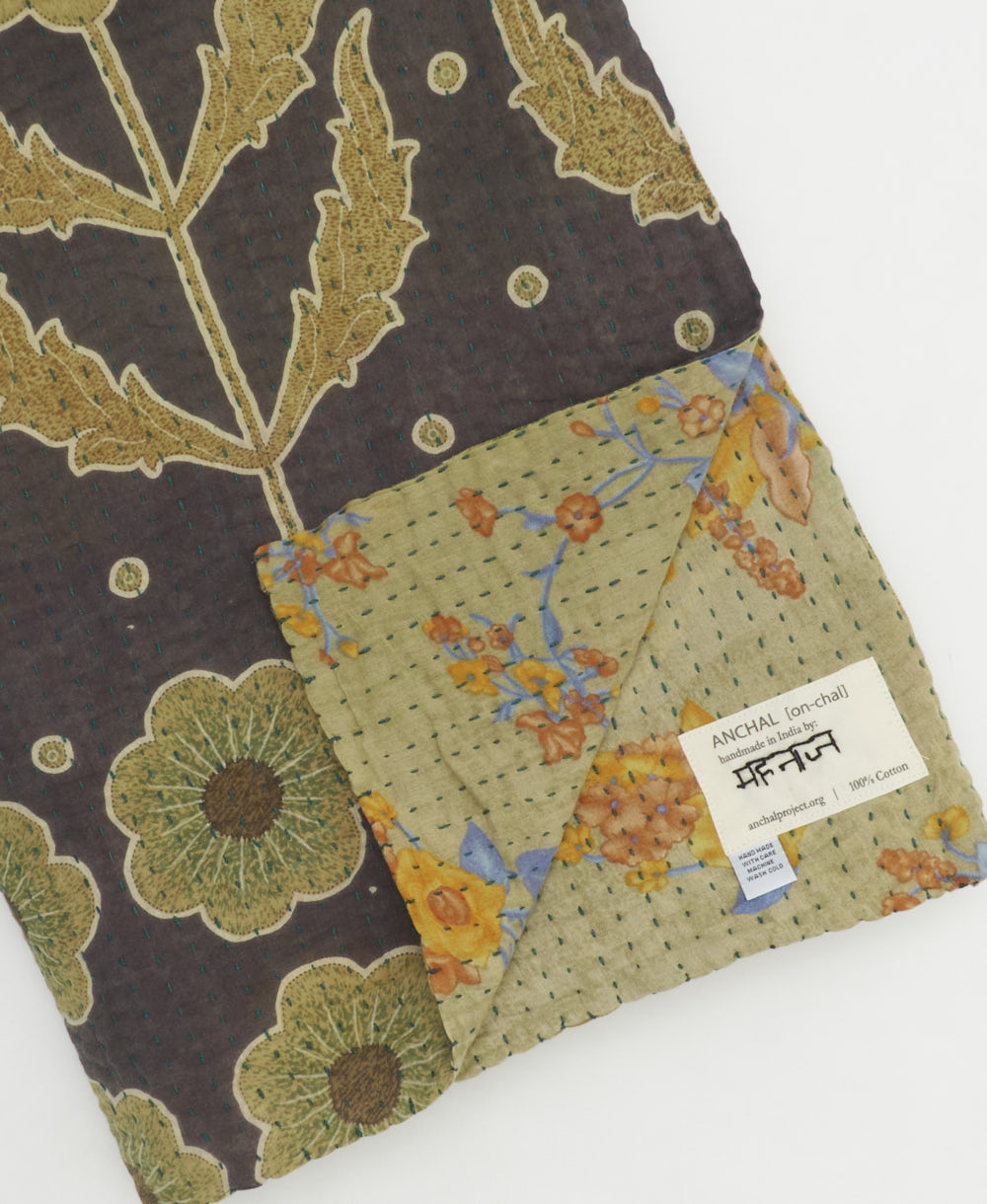 kantha quilt throw with a tag featuring the hand-stitched signature of the maker