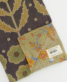 kantha quilt throw with a tag featuring the hand-stitched signature of the maker
