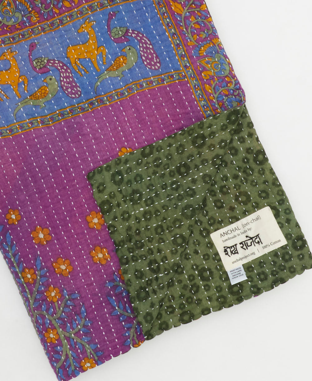 kantha quilt throw with a tag featuring the hand-stitched signature of the maker