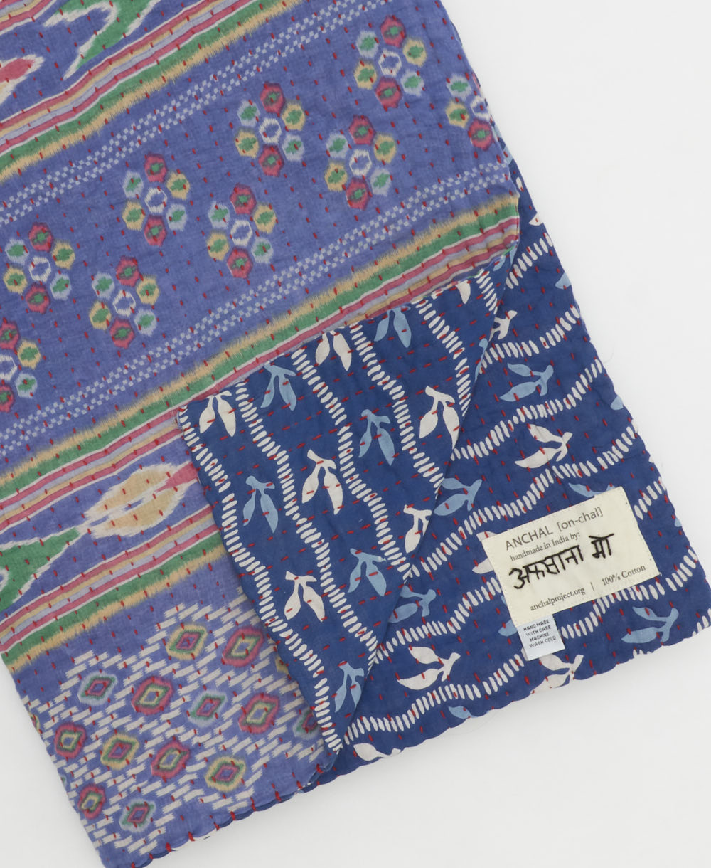 kantha quilt throw with a tag featuring the hand-stitched signature of the maker