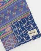 kantha quilt throw with a tag featuring the hand-stitched signature of the maker