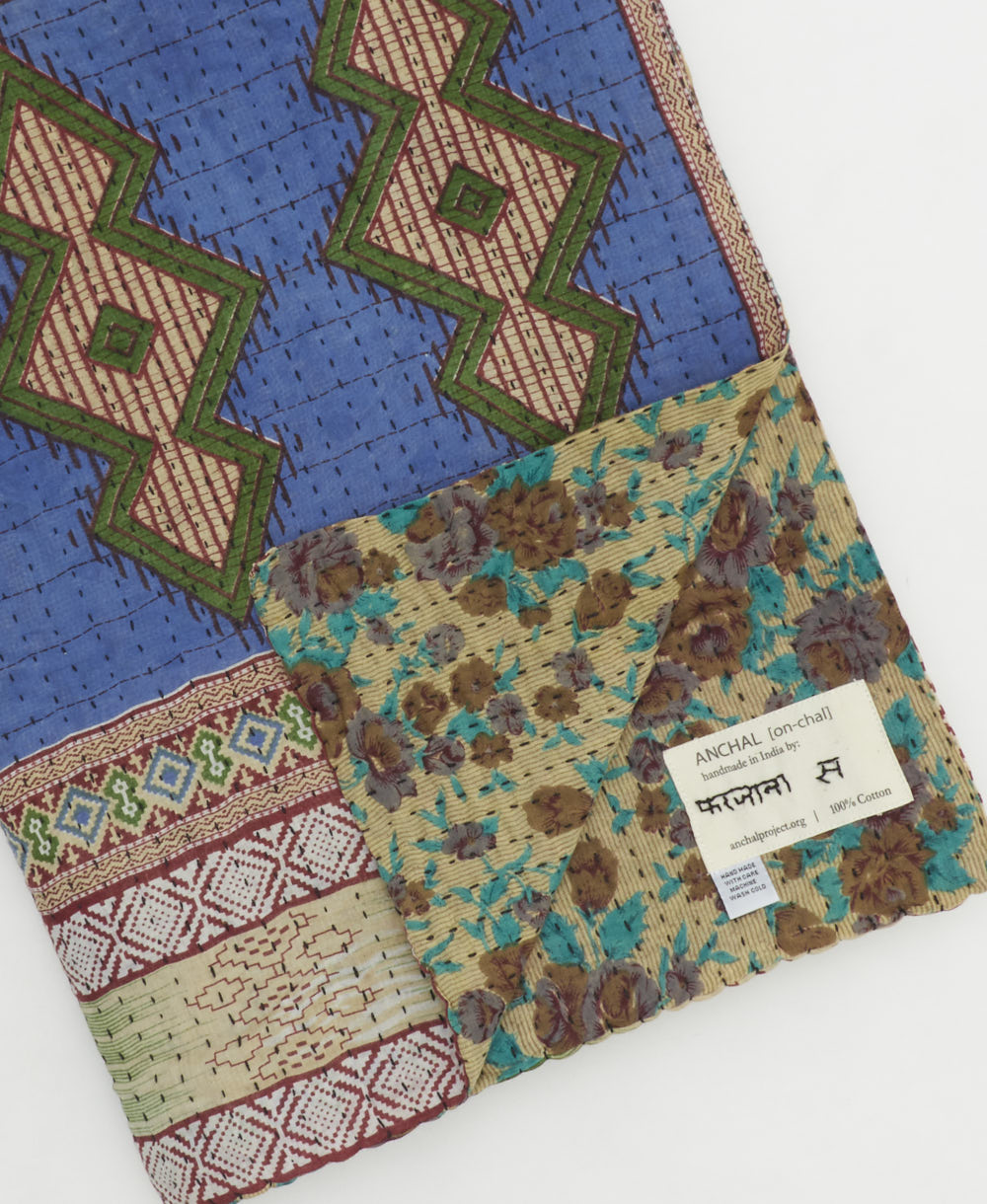 kantha quilt throw with a tag featuring the hand-stitched signature of the maker