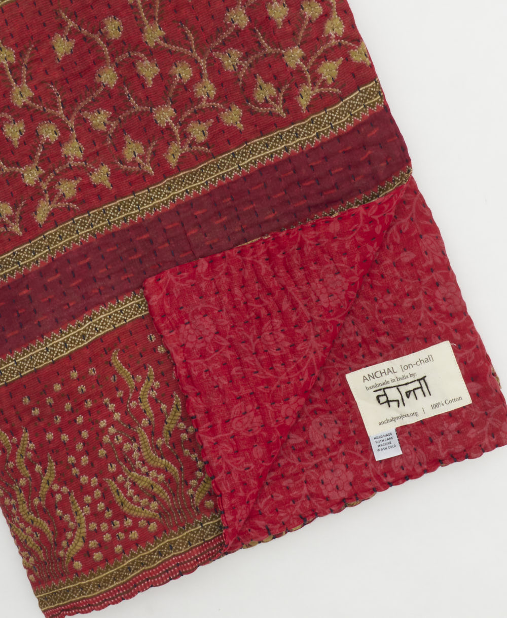kantha quilt throw with a tag featuring the hand-stitched signature of the maker