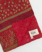 kantha quilt throw with a tag featuring the hand-stitched signature of the maker