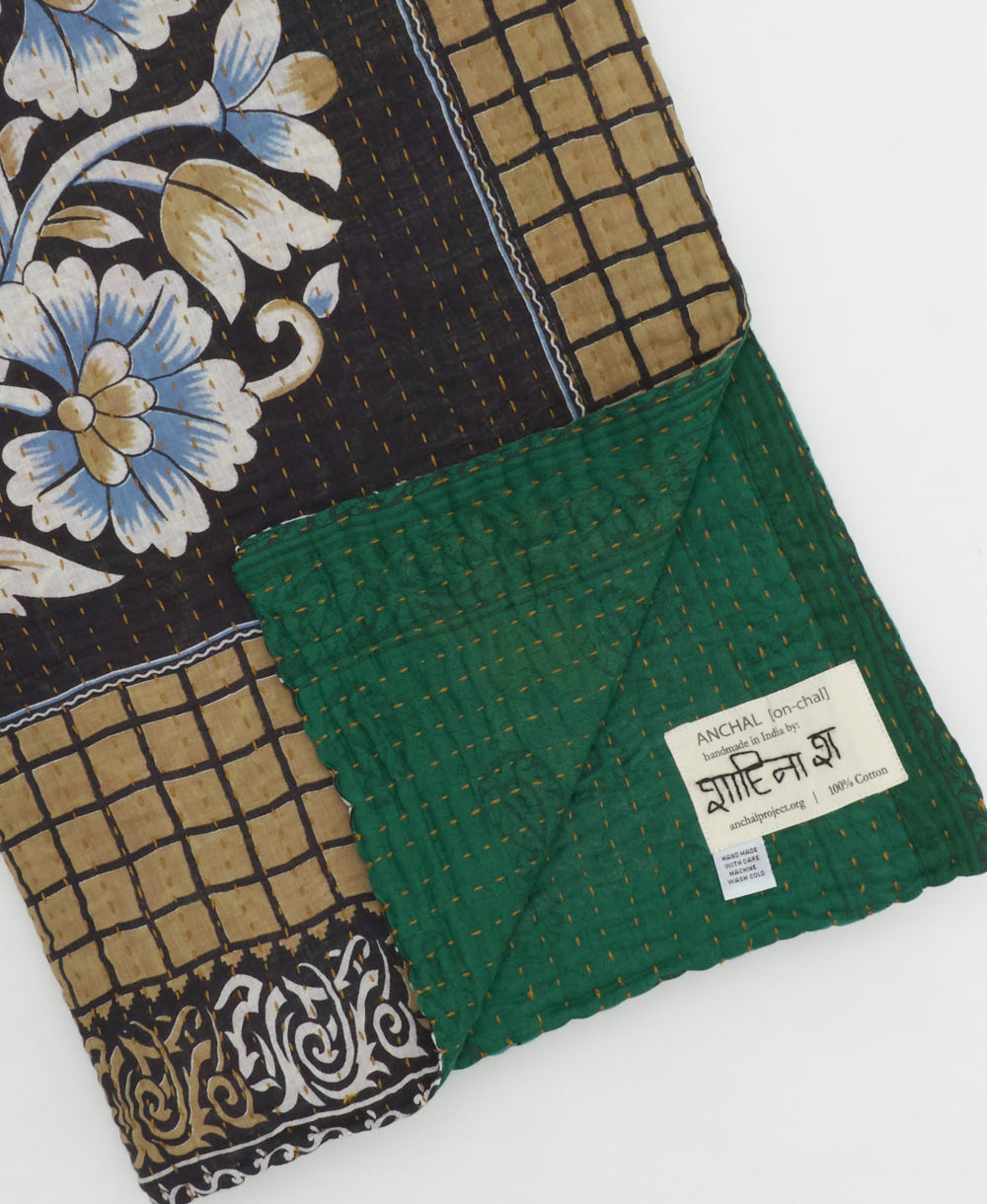 kantha quilt throw with a tag featuring the hand-stitched signature of the maker
