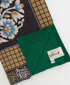 kantha quilt throw with a tag featuring the hand-stitched signature of the maker