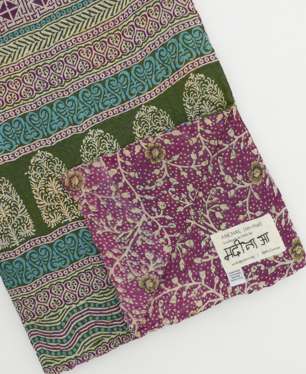 kantha quilt throw with a tag featuring the hand-stitched signature of the maker