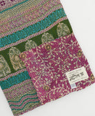 kantha quilt throw with a tag featuring the hand-stitched signature of the maker