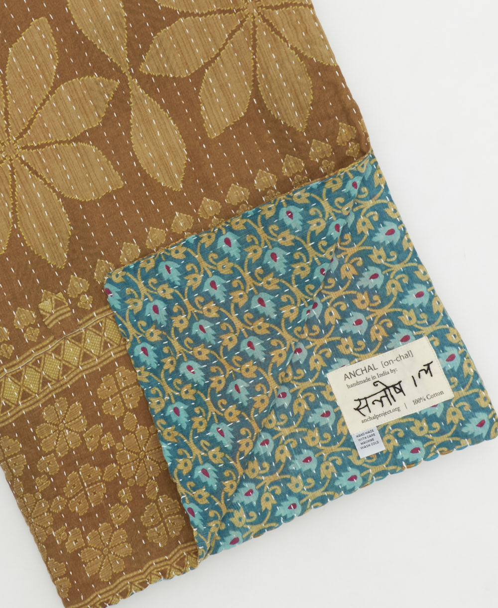 kantha quilt throw with a tag featuring the hand-stitched signature of the maker
