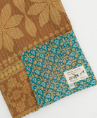 kantha quilt throw with a tag featuring the hand-stitched signature of the maker