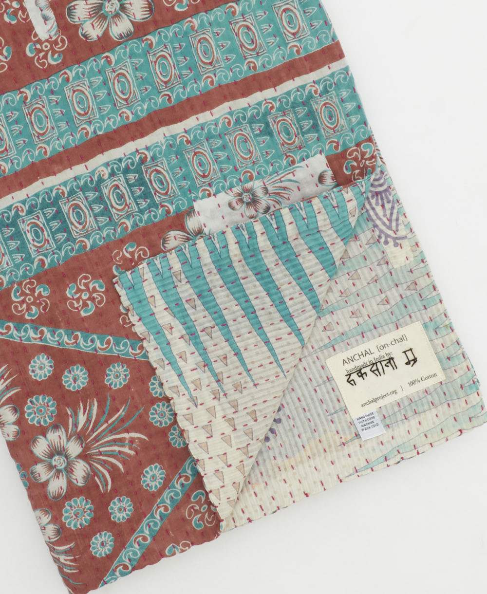 kantha quilt throw with a tag featuring the hand-stitched signature of the maker