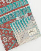 kantha quilt throw with a tag featuring the hand-stitched signature of the maker