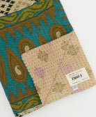 kantha quilt throw with a tag featuring the hand-stitched signature of the maker