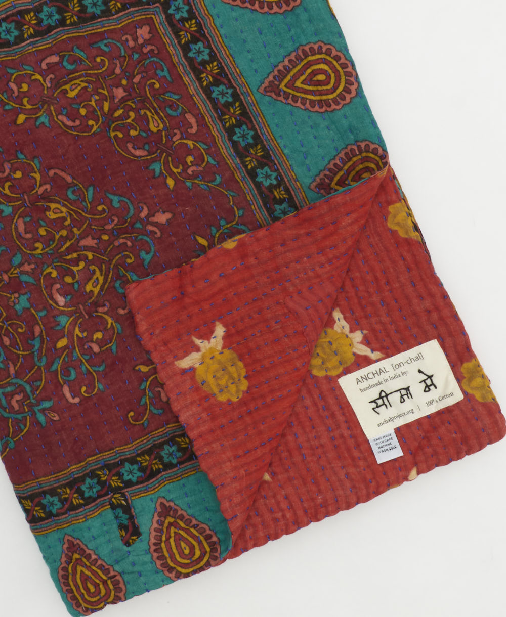 kantha quilt throw with a tag featuring the hand-stitched signature of the maker