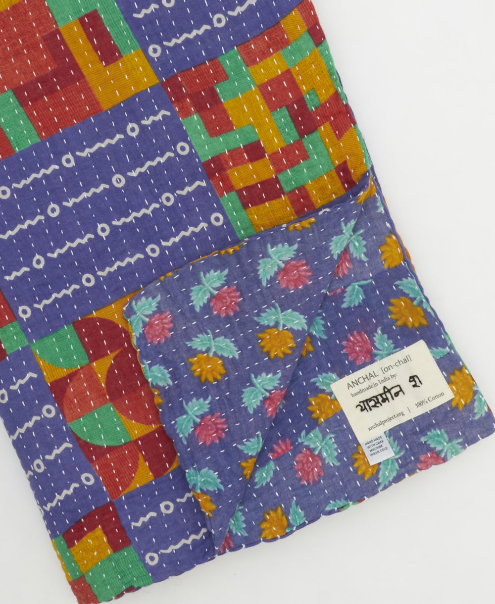 kantha quilt throw with a tag featuring the hand-stitched signature of the maker