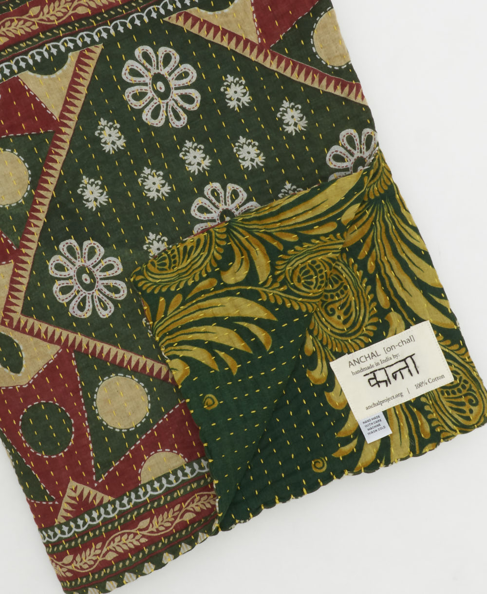 kantha quilt throw with a tag featuring the hand-stitched signature of the maker