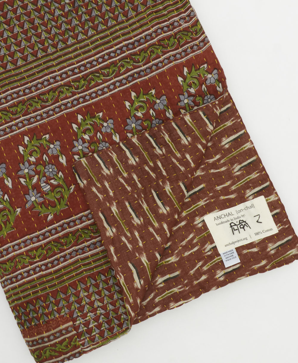 kantha quilt throw with a tag featuring the hand-stitched signature of the maker