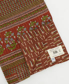 kantha quilt throw with a tag featuring the hand-stitched signature of the maker