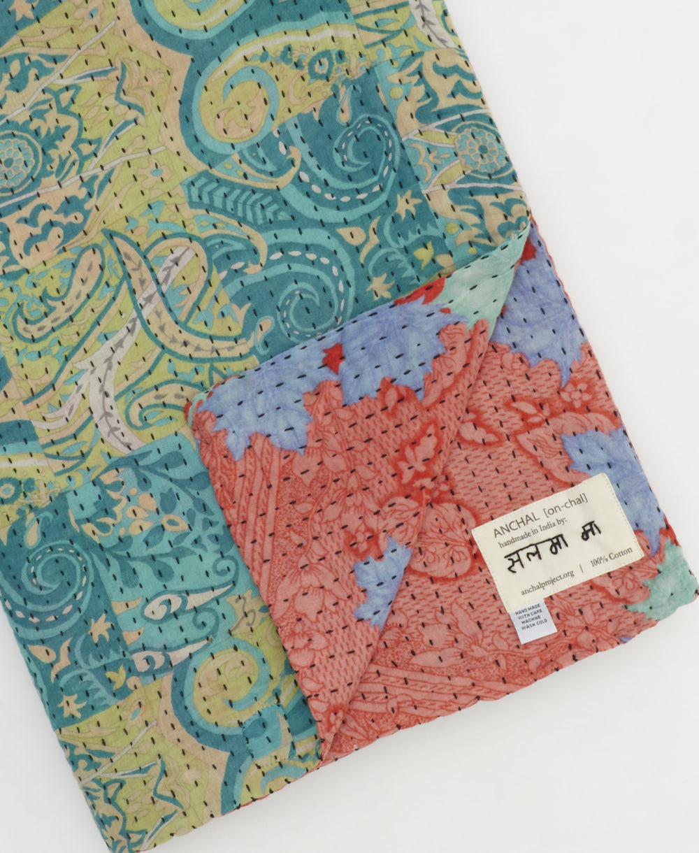 kantha quilt throw with a tag featuring the hand-stitched signature of the maker