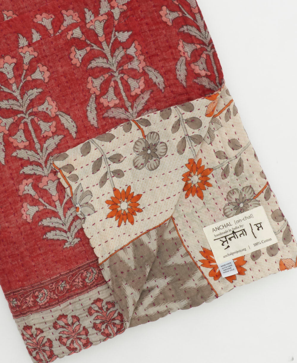 kantha quilt throw with a tag featuring the hand-stitched signature of the maker
