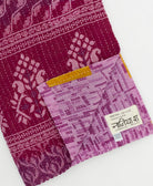 kantha quilt throw with a tag featuring the hand-stitched signature of the maker