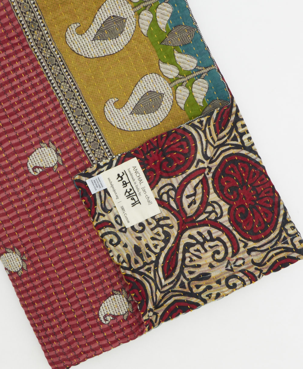 kantha quilt throw with a tag featuring the hand-stitched signature of the maker